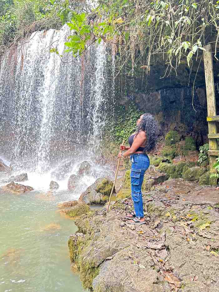 a lady holding a stick while standing next to water